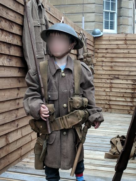 Picture of a young boy dressed up in WW1 uniform in the trench