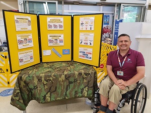 Photo of Christopher Auker-Howlett in the Churchdown Tesco branch in front of GCN Display Boards.